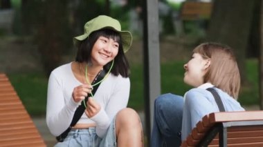 İki gülümseyen çokuluslu arkadaş bankta konuşuyor.