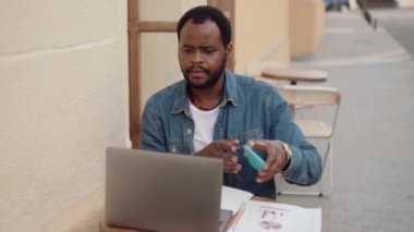 Kafede laptopla çalışan konsantre Afrikalı bir adam.