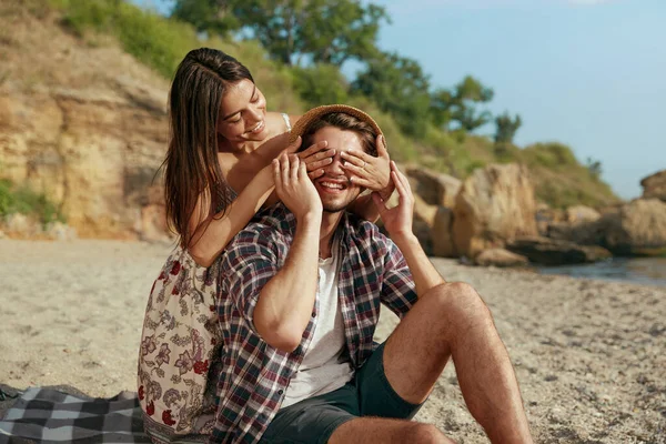 快乐的女孩闭上了她微笑的男朋友的眼睛 一对年轻的欧洲夫妇在沙滩上休息 浪漫关系的概念和享受在一起的时光 夏天的自然假期 阳光明媚 — 图库照片