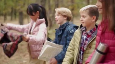 Parkta piknik yapan pozitif çokuluslu bir grup çocuk.