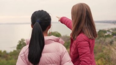 Arka planda iki küçük kız deniz manzarasına bakıyor ve dışarıyı işaret ediyor.