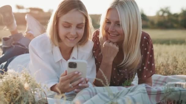 Twee Gelukkige Vrouwen Kijken Naar Telefoon Terwijl Liggend Ruit Picknick — Stockvideo