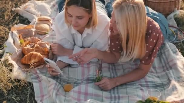 Två Stiliga Kvinnor Tittar Telefonen Medan Ligger Rutig Picknick — Stockvideo