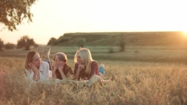 Mutlu aile gün batımında piknikte ekose üzerinde yatıyor.