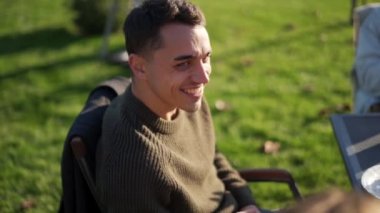 Gülen adam piknik zamanı arkadaşlarını dinliyor.