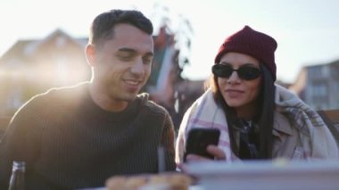Mutlu adam ve kadın piknikte telefona ve yan tarafa bakıyor.