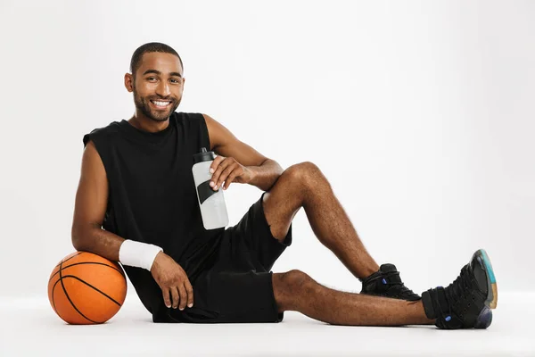 Joven Deportista Negro Bebiendo Agua Mientras Posa Con Baloncesto Aislado — Foto de Stock