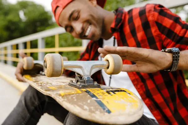 Glimlachende Jonge Afrikaanse Man Casual Kleding Zittend Met Skateboard Buiten — Stockfoto