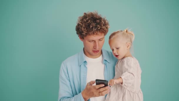 Sonriente Padre Con Hija Mensajes Texto Por Teléfono Estudio Azul — Vídeo de stock