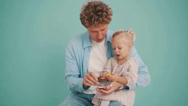 Padre Positivo Dando Huevo Chocolate Hija Estudio Azul — Vídeos de Stock
