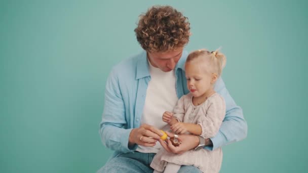 Pai Filha Positivos Abrindo Brinquedo Ovo Chocolate Estúdio Azul — Vídeo de Stock