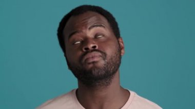 Tişört giyen dalgın Afrikalı adamın mavi stüdyoda olumlu cevap verdiği yakın plan görüntüler.