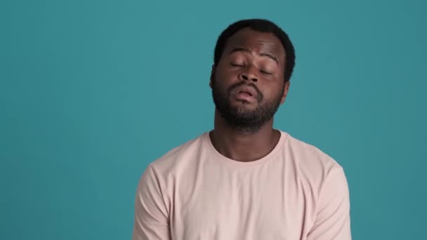 Nudný Africký Muž Tričku Ukazuje Tvář Palmové Gesto Modrém Studiu — Stock video