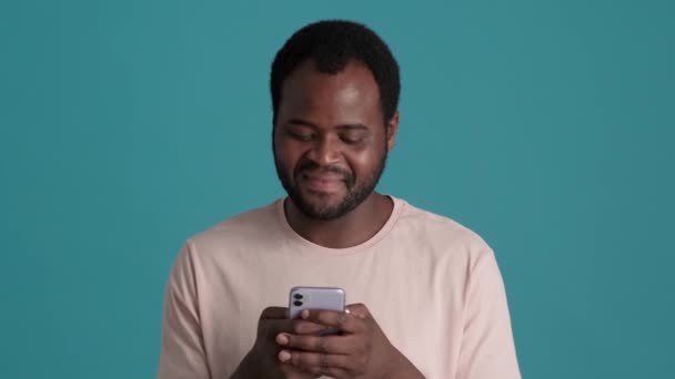 Glimlachende Afrikaanse Man Draagt Shirt Sms Telefoon Blauwe Studio — Stockvideo