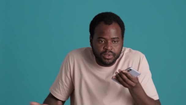 Συναισθηματικός Αφρικανός Που Φοράει Shirt Ηχογραφώντας Φωνητικό Μήνυμα Τηλεφωνικά Μπλε — Αρχείο Βίντεο