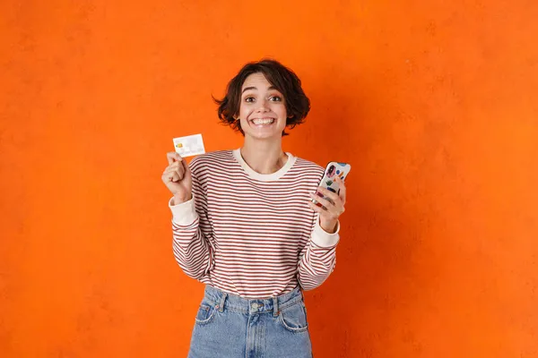 Молодая Брюнетка Женщина Позирует Кредитной Картой Мобильный Телефон Изолирован Через — стоковое фото