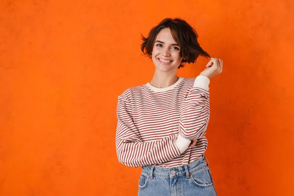 Joven Morena Sosteniendo Cabello Mirando Lado Aislado Sobre Pared Naranja — Foto de Stock