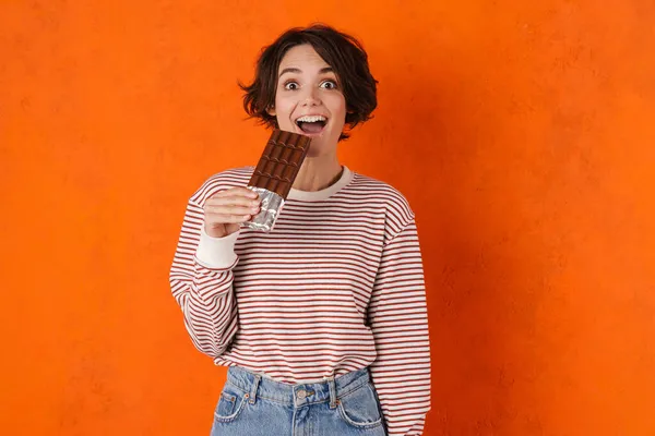 Jeune Femme Brune Souriante Tout Mangeant Chocolat Isolé Sur Mur — Photo