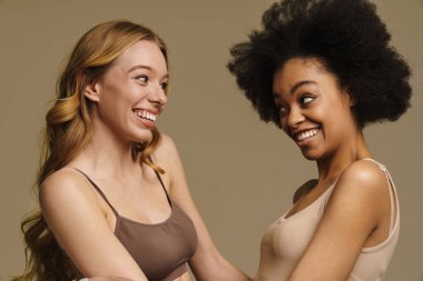 Bej arka planda duran iç çamaşırlı iki farklı genç kadın. Yakın plan.