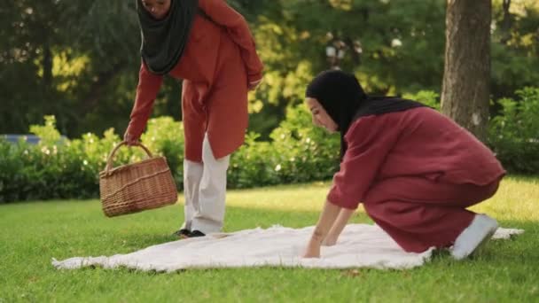 Twee Knappe Moslimvrouwen Liggend Een Picknickdeken Buiten — Stockvideo