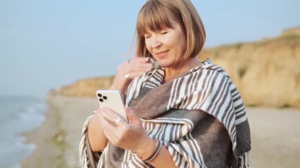 Przystojna Dojrzała Kobieta Patrzy Telefon Masuje Czoło Plaży — Wideo stockowe