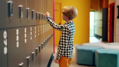 Dolabından sırt çantası alan bir çocuğun yan görüntüsü.