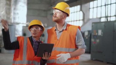 İki kendinden emin mühendis çalışan bir projeyi tartışıyor ve tablete bakıyor.