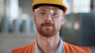 Üniformalı gülümseyen mühendis kameraya bakıyor.