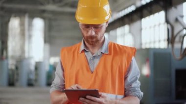 Tablet üzerinde hesap yapan üniformalı ciddi bir mühendis.