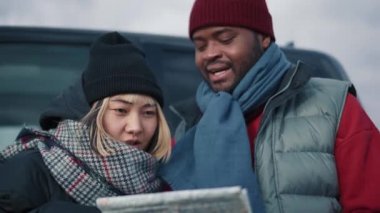 Arabanın yakınındaki haritaya bakan çok uluslu pozitif turist çiftin yakın görüntüsü.