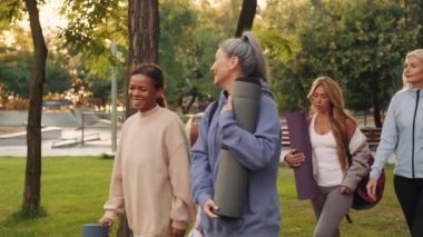 Neşeli, çok uluslu olgun kadınlar yogaya gidiyor ve dışarıda konuşuyorlar.