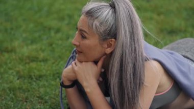 Parkta yoga minderinde yatan Asyalı kadının yan görüntüsü
