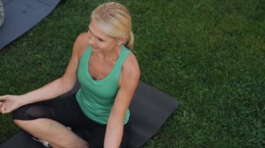 Yoga minderi üzerinde meditasyon yapan olgun kadınların en iyi görüntüsü.