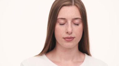 Beyaz stüdyoda kameraya bakan güzel bir kadının portresi.