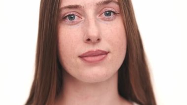 Beyaz stüdyoda kameraya poz veren mutlu kadının yakın çekim görüntüsü.