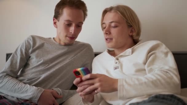 ハンサムなゲイのカップルは 電話を見て ベッドで話して — ストック動画