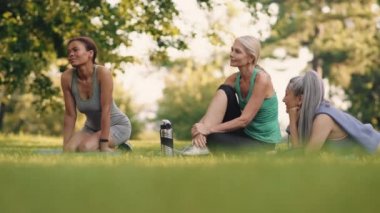 Yoga minderinde konuşan çok uluslu olgun kadınlar.