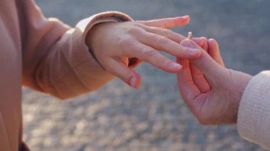 Erkek eli, kadın parmağına yüzük takarken yakın plan bir çekim.