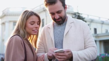 Telefona bakıp, farklı yönlere bakan pozitif bir çift.