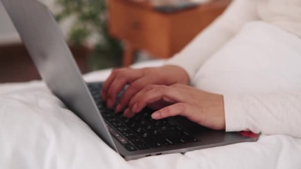 ベッドの中でノートパソコンで入力する女性の手のクローズアップビュー — ストック動画