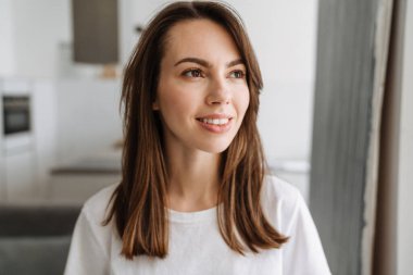 Genç beyaz kadın gülümsüyor ve içeri bakıyor.