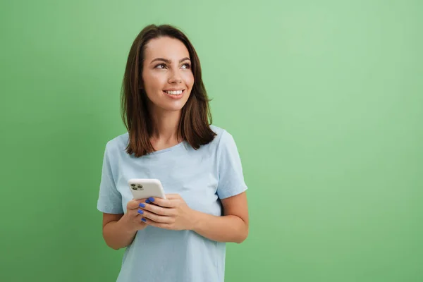 年轻的欧洲女人穿着T恤笑着用绿色背景的手机 — 图库照片