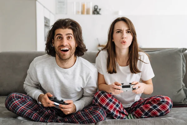 Joven Pareja Feliz Sosteniendo Joysticks Jugando Juegos Pantalla Televisión Mientras —  Fotos de Stock