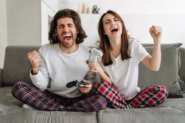Młoda Szczęśliwa Para Trzyma Joysticks Grając Gry Ekranie Telewizora Podczas — Zdjęcie stockowe
