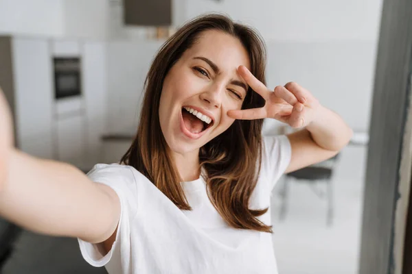 Mladá Bílá Žena Usmívá Gestikuluje Při Focení Selfie Uvnitř — Stock fotografie