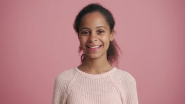 Pozitif Afrikalı küçük kız pembe stüdyoda seviniyor.