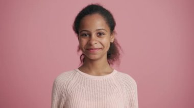 Pozitif Afrikalı küçük kız pembe stüdyoda seviniyor.
