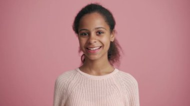 Pozitif Afrikalı küçük kız pembe stüdyoda seviniyor.