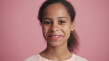 Pozitif Afrikalı küçük kız pembe stüdyoda seviniyor.