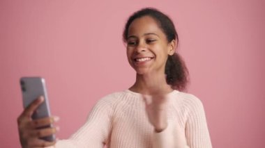 Pozitif Afrikalı küçük kız pembe stüdyoda seviniyor.